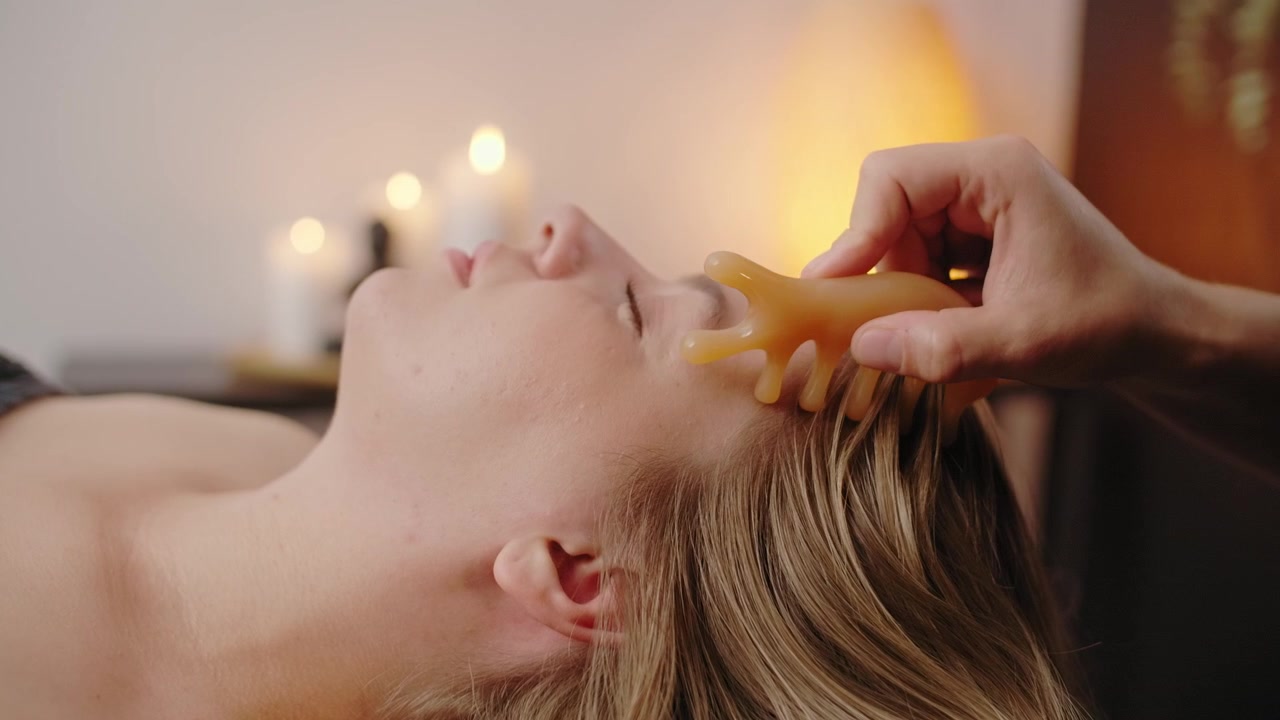 Professionel terapeut udfører Gua Sha hovedmassage på afslappet kvinde