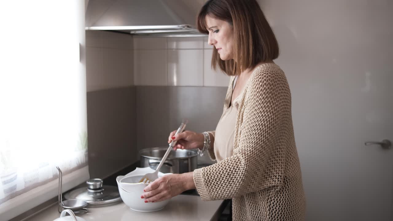 woman transferring meat with sauce from a pot to a ceramic bowl to serve