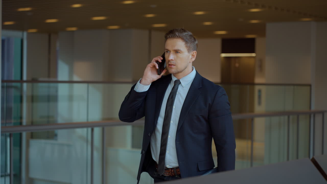 Caucasian Businessman Talking on Phone While Walking Through Long Office Corridor - slow motion