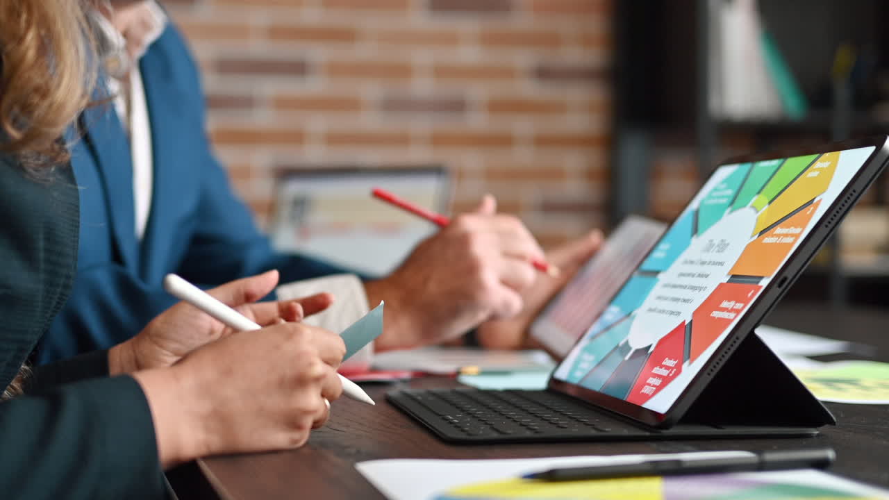 En mand og en kvinde, der analyserer et diagram på en tablet ved et bord på et kontor