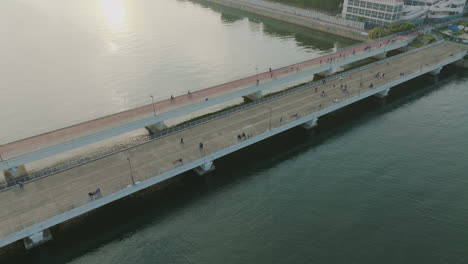 beautiful circular shot of a bridge over a river with people and bicycles over it