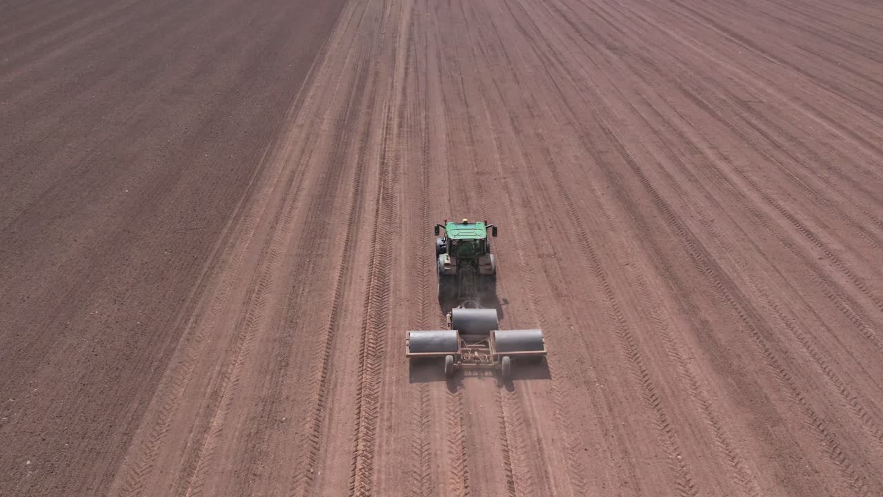 vista aérea de pájaros de la tierra aplanada del tractor usando rodillos pesados, campo grande