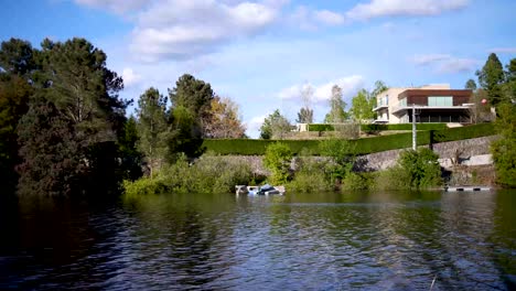 boat floating on a calm lake shore with glamorous house on a sunny day