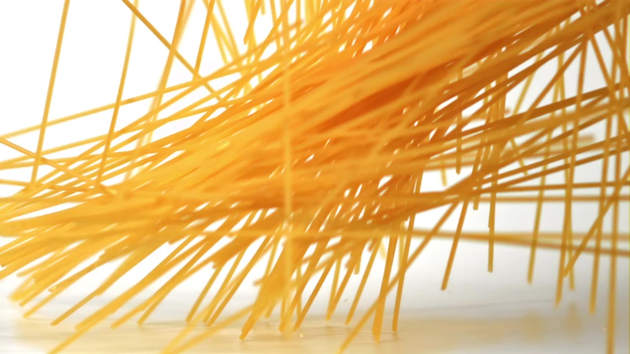Spaghetti secchi che cadono al rallentatore su uno sfondo bianco