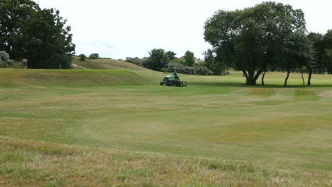 mowing grass lawn green on a golf course with a ride on mower