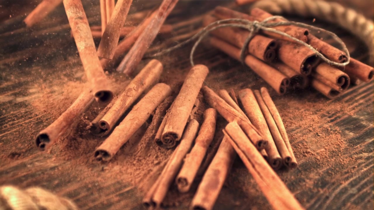 Canela em pó caindo sobre paus de canela e mesa de madeira