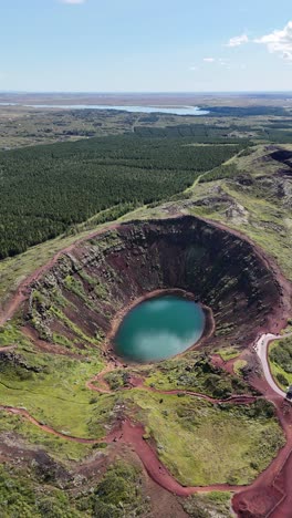 stunning aerial view of the kerid crater with lush green landscapes, vertical video.
