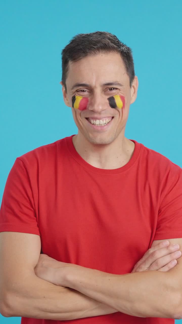 Man standing with belgian flag painted on face smiling