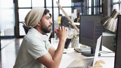 young asian man in a business office setting, focused on his computer screen