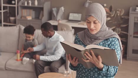 muslim woman in hijab reading quran at home