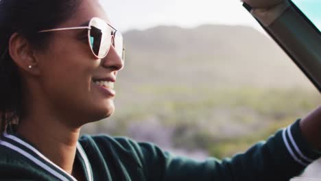 mujer afroamericana conduciendo por una carretera de campo en un coche descapotable