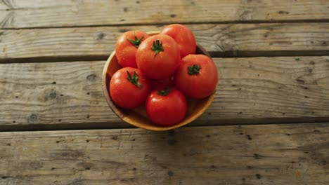 video de tomates frescos en un cuenco sobre un fondo de madera