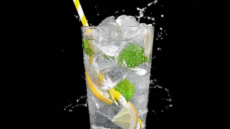 vaso de limonada con menta y hielo salpicado con agua sobre el fondo amarillo en cámara lenta