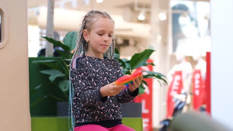 little girl plays with pop it fidget toys in mall
