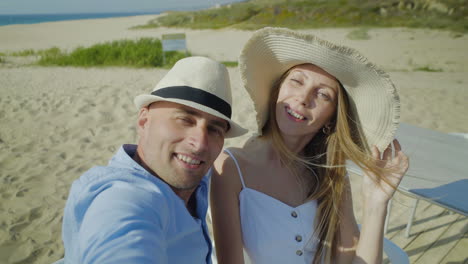 una joven pareja feliz tomando una selfie en la playa
