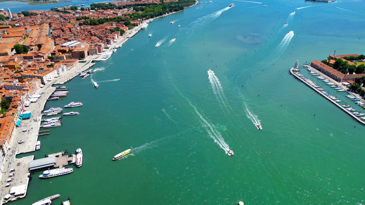 Vista aerea con drone di Venezia, Italia. Canale d'acqua con numerose barche ormeggiate e galleggianti, centro storico con edifici antichi e stradine strette
