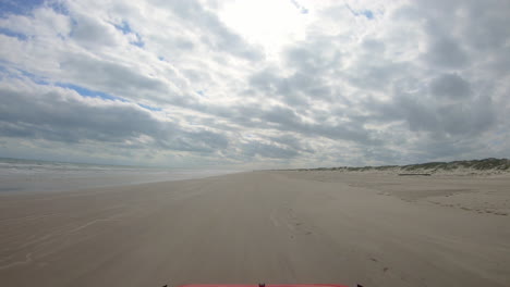 POV-Durch-Die-Windschutzscheibe-Des-Fahrzeugs,-Das-Am-Strand-Zwischen-Brandung-Und-Dünen-Der-North-Padre-Island-National-Seashore-Fährt.-Andere-Urlauber-Am-Strand-An-Einem-Bewölkten-Tag