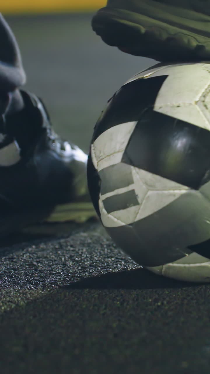 Close-up of a soccer player s right foot gently rolling a soccer ball on artificial turf, textured ground surface, dynamic movement, and focus on footwork under nighttime