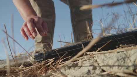 female warrior putting the shotgun on the ground and sitting down