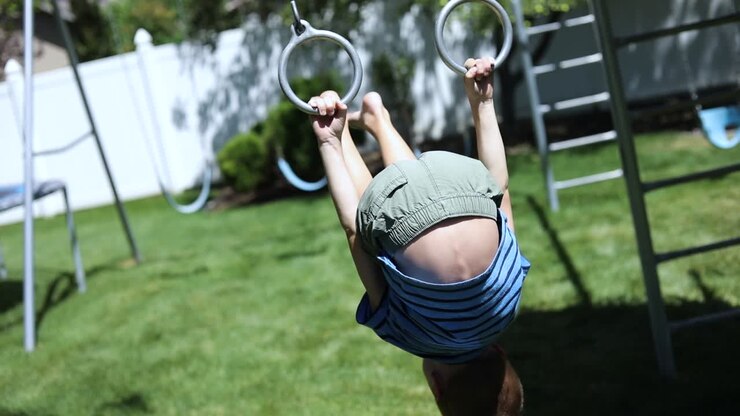 Slow Motion shot of a young boy playing on the monkey bars on a playground set in his backyard
