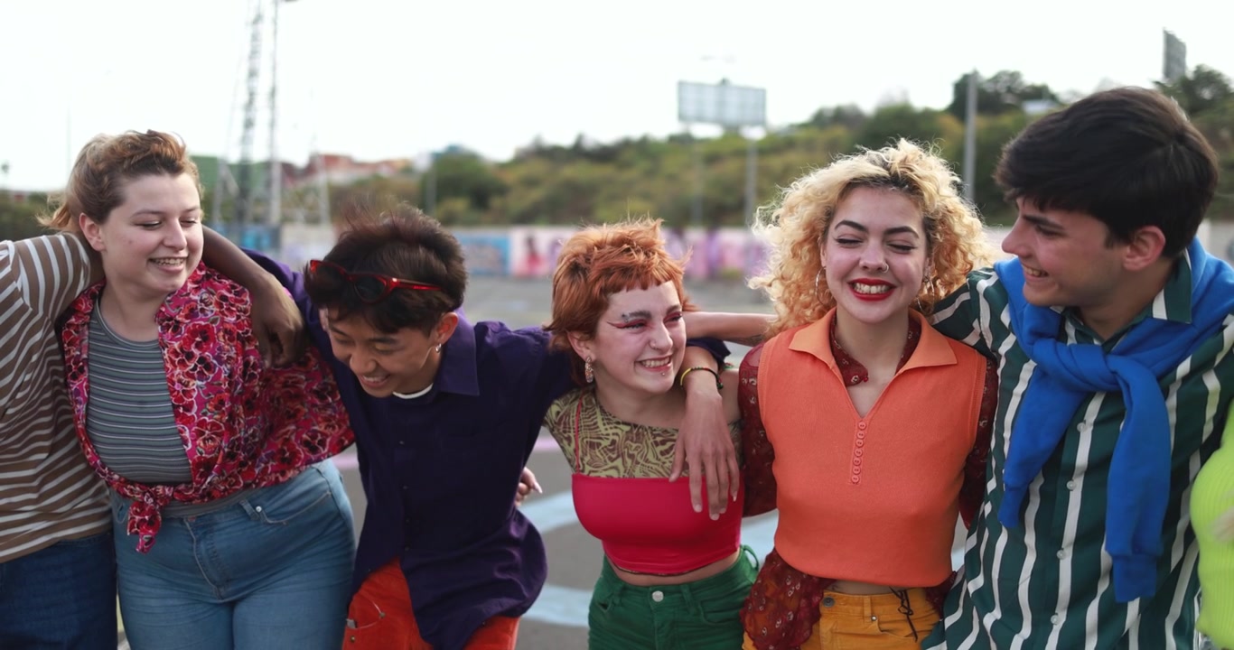 Jóvenes amigos diversos riendo y abrazándose al aire libre