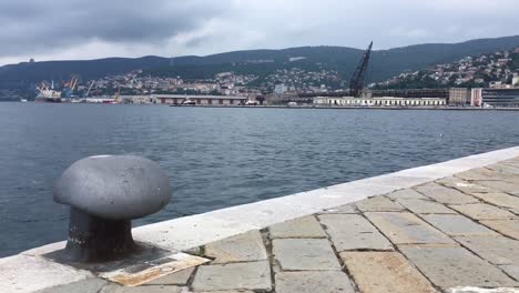 Stone-pier-by-the-sea,-city-in-the-distance