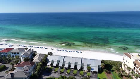 aerial fly over the coastal settlement with apartments and turquoise ocean along white sandy beach, 30a, florida, usa