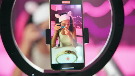 woman recording beauty tutorial with ring light and smartphone