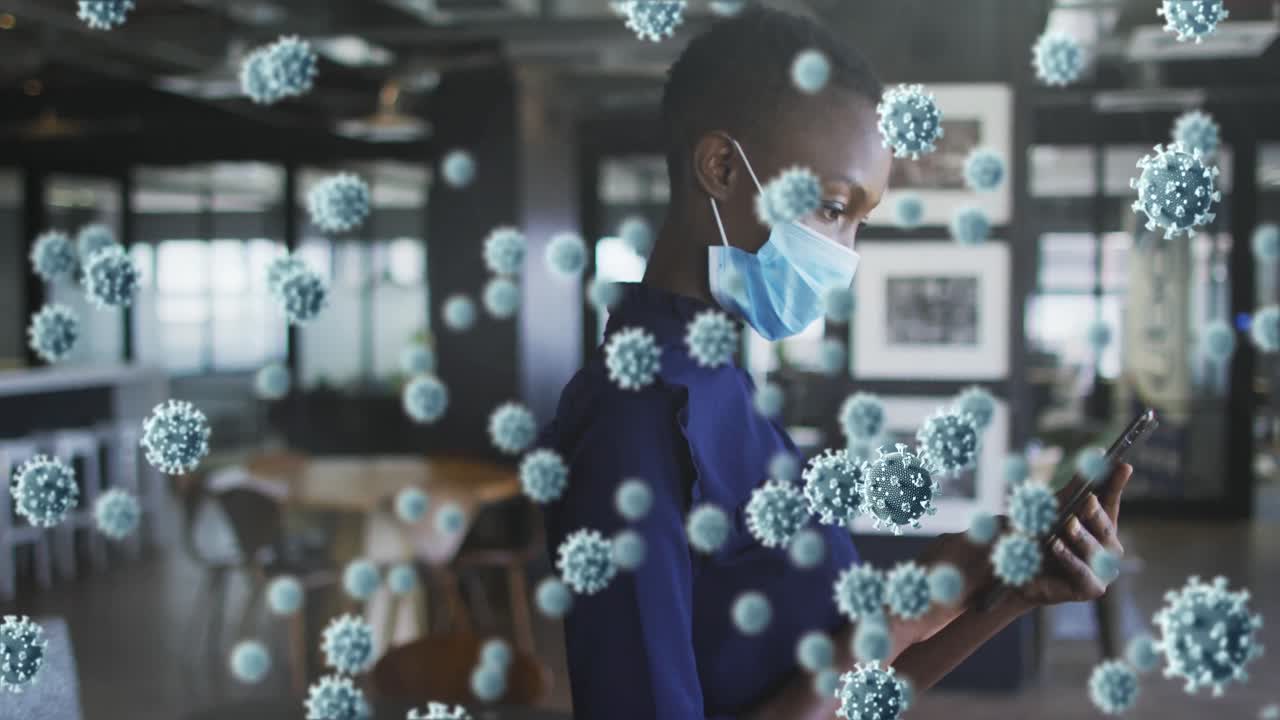 Animation of covid 19 cells floating over woman in face mask using smartphone in office