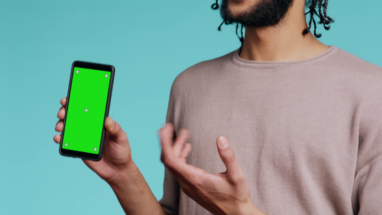 hombre feliz señalando hacia la pantalla verde del teléfono móvil, mostrando el pulgar hacia arriba señal