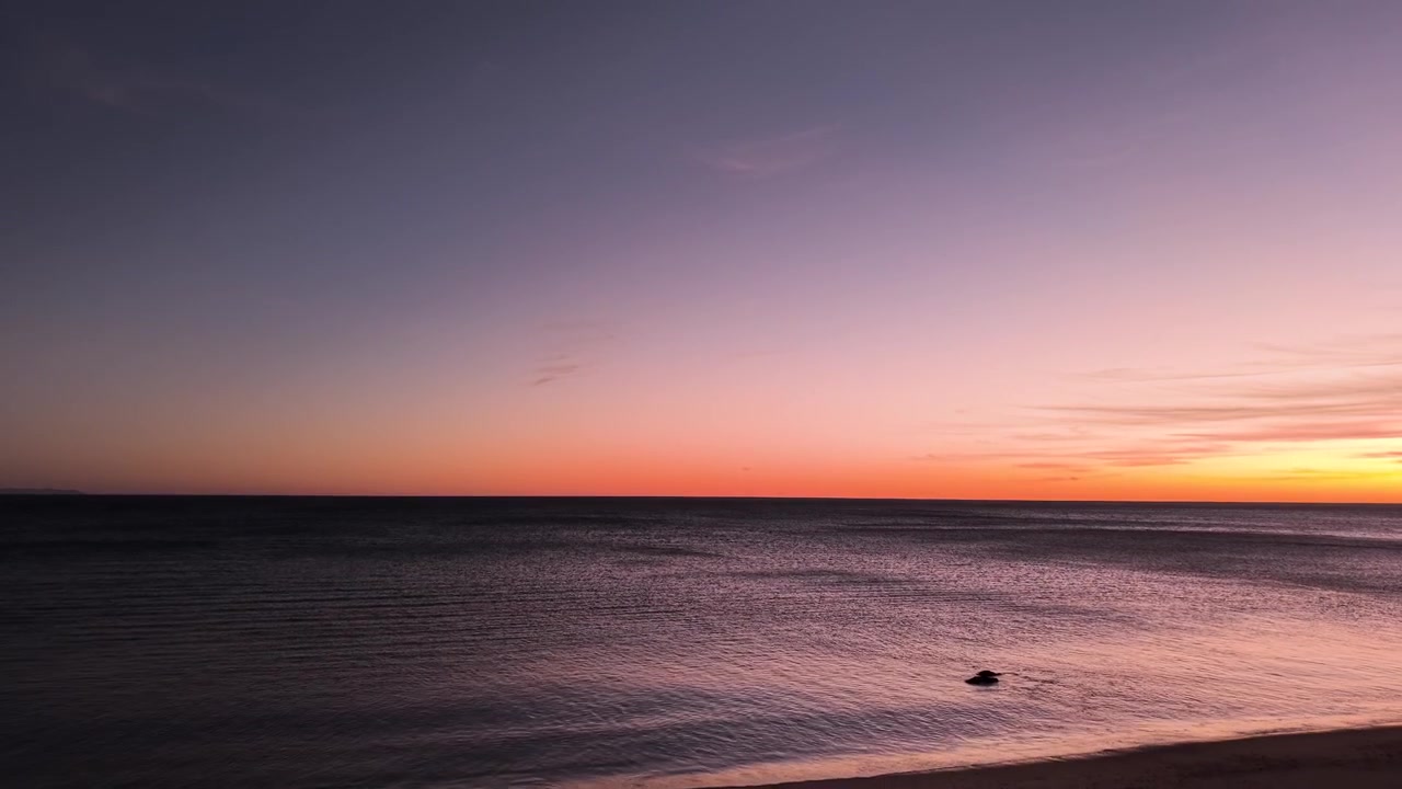 Pacific Ocean horizon stretches across the frame in a minimalist California coastal moment, sky and water meeting in the simplest expression of the open sea at sunset.