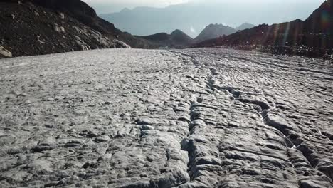 Push-in,-large-glacier-in-the-swiss-alps-with-rifts-and-crevasses,-global-warming-pressure,-sunrise-captured-by-drone