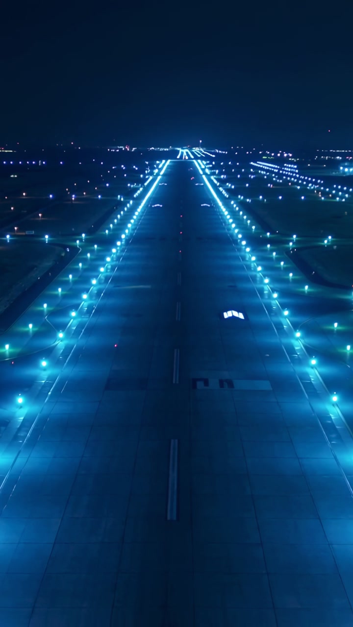 Approaching runway and blue teal edge lights at airport at night, showing centerline markings