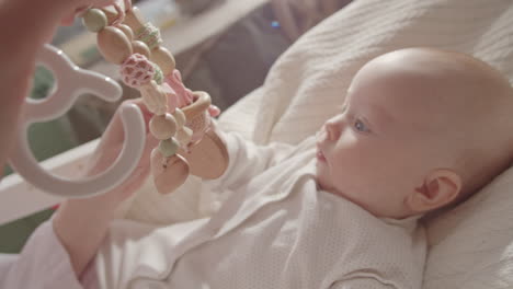 baby girl playing with wooden toy mobile