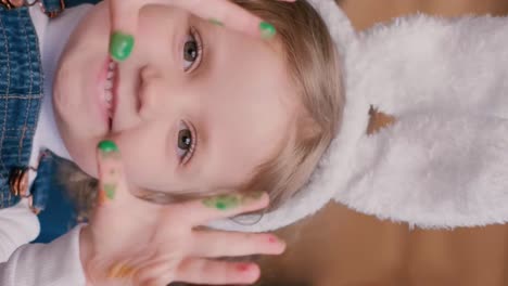 a child with bunny ears is playing with colored eggs in her hands. easter holiday concept