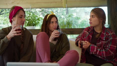 Shooting-close-up,-a-brunette-girl-tells-her-friends-stories-from-life.-At-the-same-time,-they-drink-tea-in-a-gazebo-in-nature