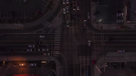 Road-intersection-at-dusk-with-car-traffic-passing-and-parking-lot-in-Los-Angeles,-California,-Aerial-Birds-Eye-Overhead-Top-Down-View-from-above