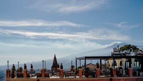 rooftop terrace in taormina with a clear view to mount etna. timelapse video with smoke coming out of a volcano summit in a sunny summer day.