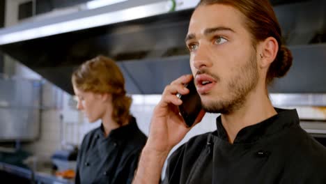 Chef-looking-at-clipboard-while-talking-on-mobile-phone-4k