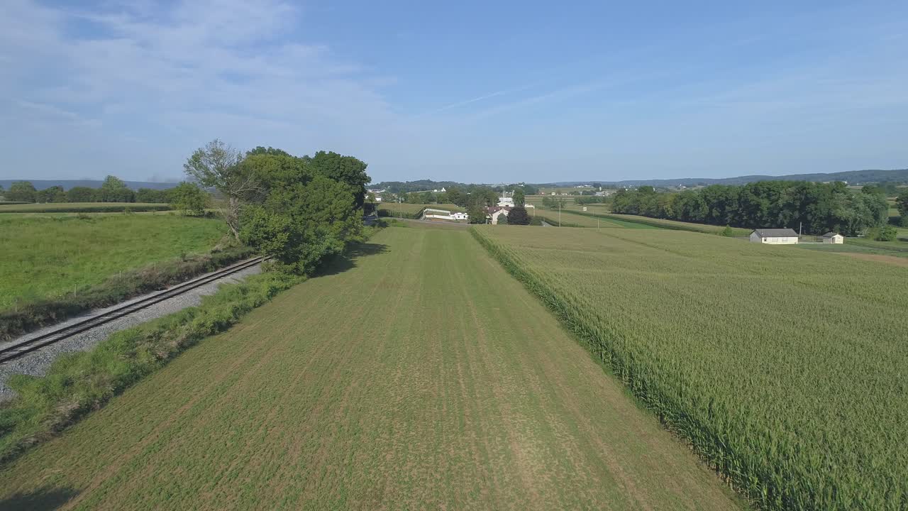 Veduta aerea ravvicinata di campi agricoli verdi accanto a un binario ferroviario nella campagna Amish in una soleggiata giornata estiva