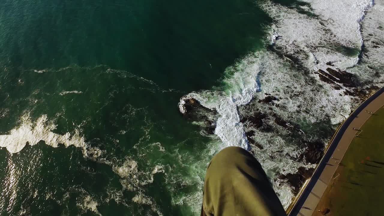 pov de un parapente volando sobre el océano y el paseo marítimo