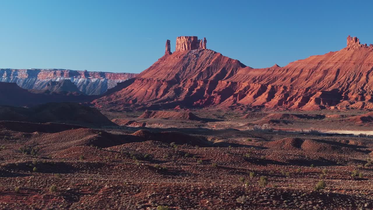Aerial establishing ascend of deep red Moab canyon with winding roads cutting through rugged desert terrain