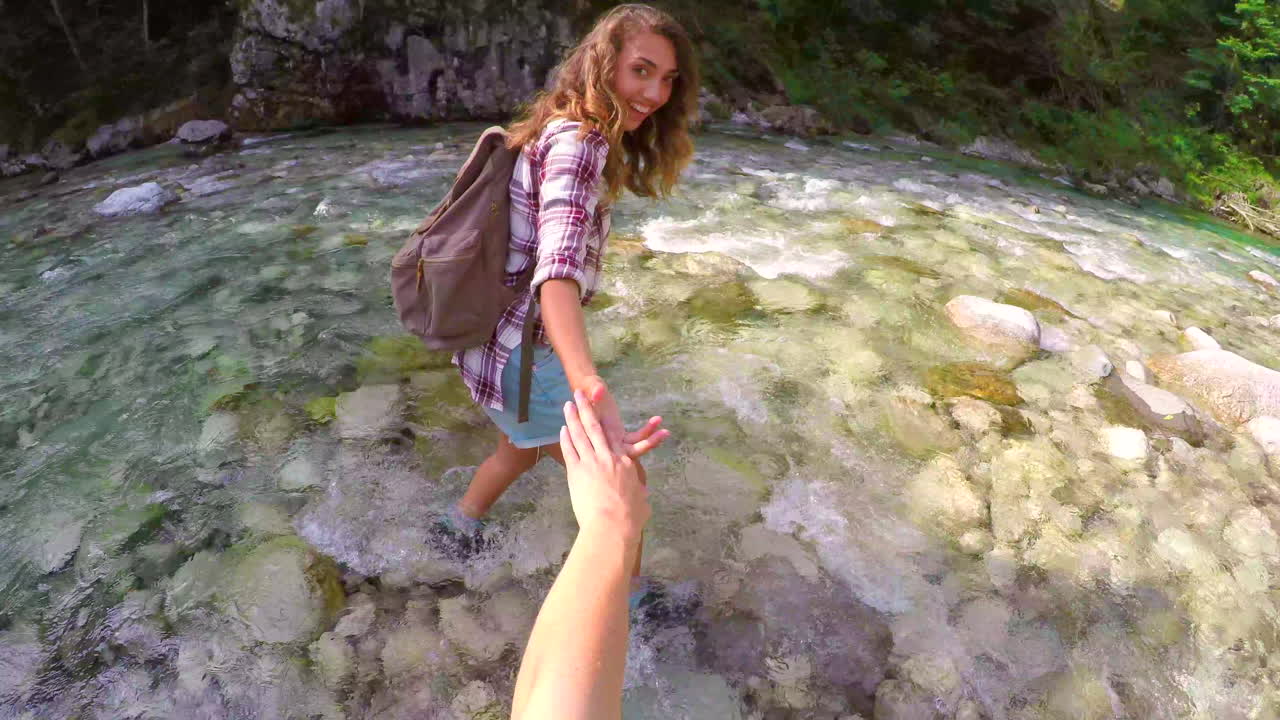 mujer joven feliz caminando a través de un río