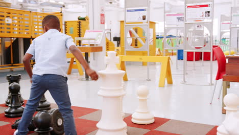 grupo de niños jugando al ajedrez gigante en el centro de actividades científicas