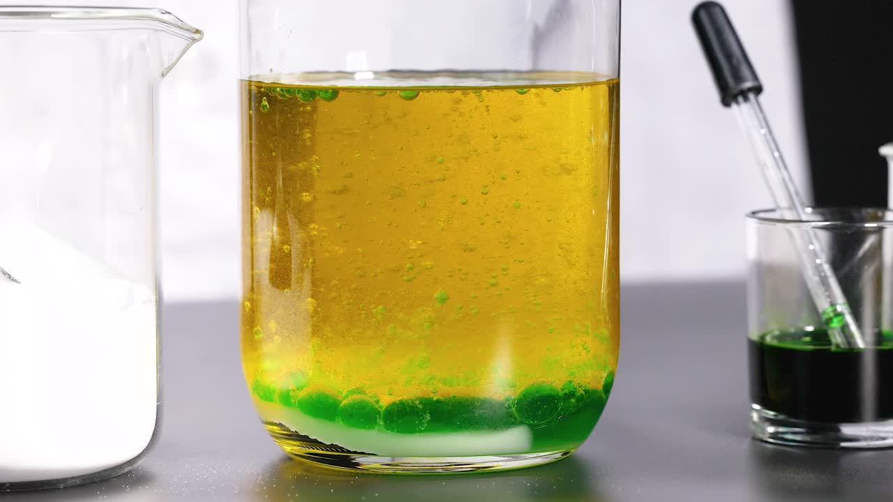 실험실 실험은 밀도 차이를 보여주는 컵에서 분리되는 색 액체와 화학 반응을 보여줍니다.