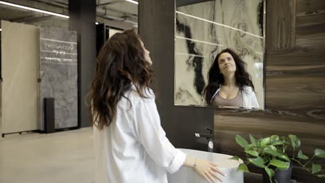 a woman examines a stylish round mirror in a modern furniture store a woman examines a stylish round mirror in a modern furniture store imagining how it would fit into her bathroom decor and focusing on the details to choose the perfect piece