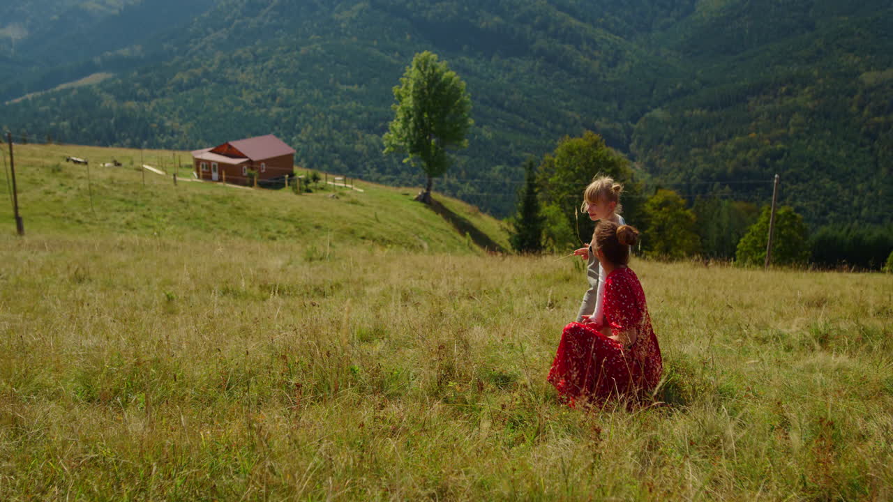 젊은 어머니가 초원에서 딸을 앉히고, 산에서 여자와 함께 휴식을 취하는 여자.