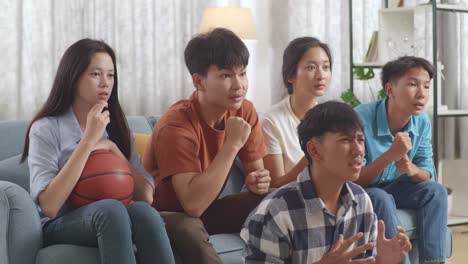 asian teenagers cheering and watching basketball game on tv and disappointed at home