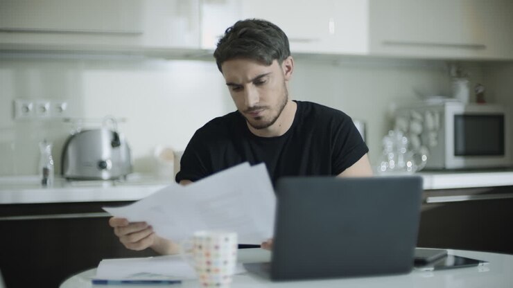 Tankefuld mand arbejder med dokumenter derhjemme. Forretningsmand laver papirarbejde