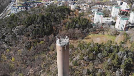 Toma-Aérea-De-Una-Pila-De-Humo-De-La-Chimenea-De-La-Planta-De-Calefacción-Y-Una-Pequeña-Ciudad-En-Suecia